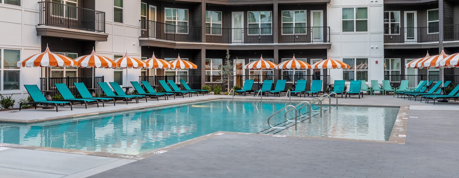 a courtyard with a pool, chairs and umbrellas